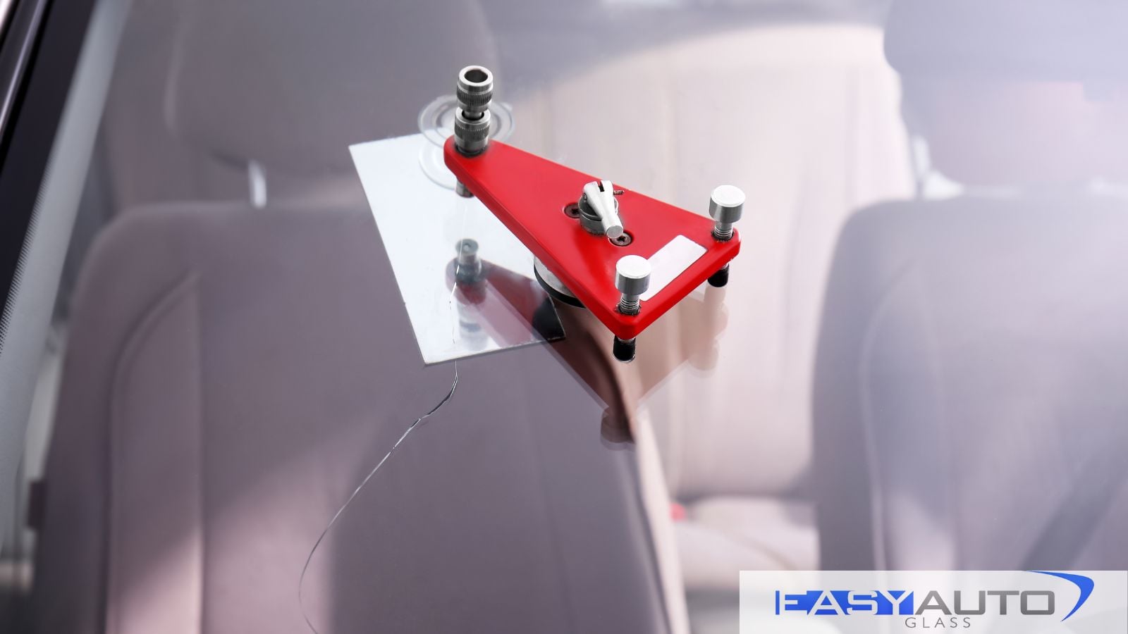 A windshield crack with a windshield repair tool over it. Be sure to repair or replace your windshield as quickly as needed.